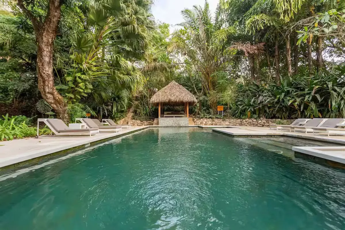 Balinese-style pool with sun loungers and a thatched palapa
